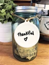 A mason jar with a tag that says `` thankful '' is sitting on a wooden table.