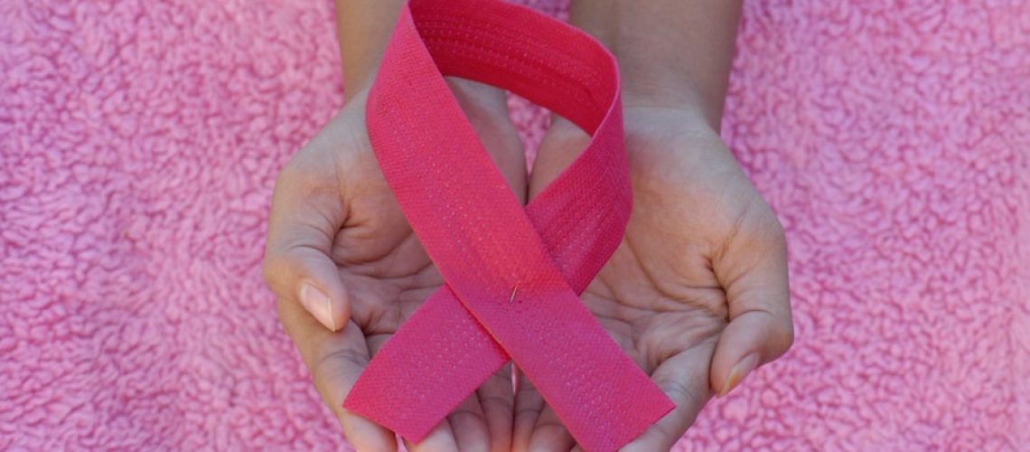 A person is holding a pink ribbon in their hands.