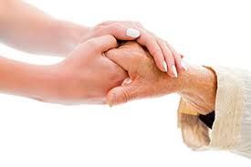 A woman is holding the hand of an older woman.