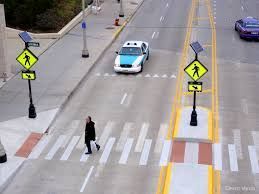A man is crossing the street at a crosswalk with a car driving by.