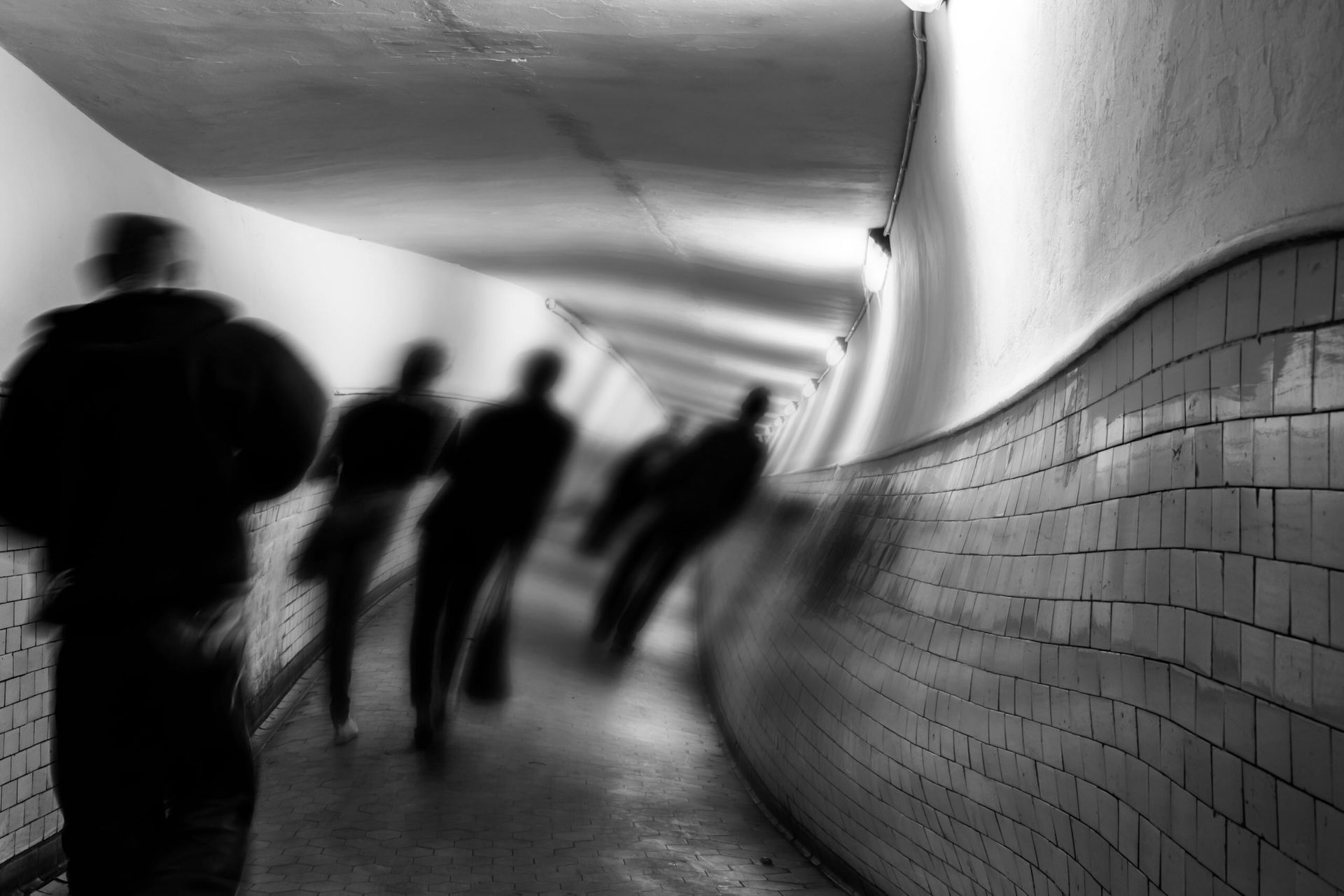A group of people are walking down a tunnel in a black and white photo.