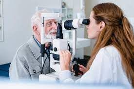 An elderly man is getting his eyes examined by an ophthalmologist.