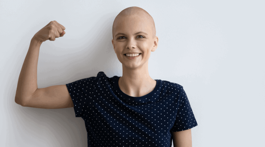 A woman with cancer is smiling and flexing her muscles.