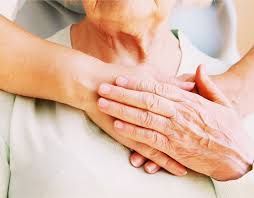 A close up of a person holding another person 's hand on their chest.