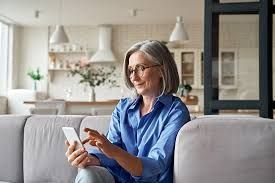 A woman is sitting on a couch using a tablet computer.
