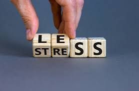 A person is holding wooden cubes with the words less stress written on them.