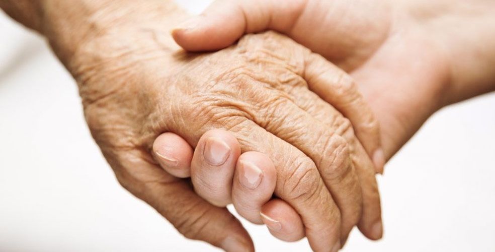A close up of a person holding an older person 's hand.