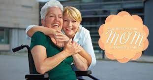 A nurse is hugging an older woman in a wheelchair.