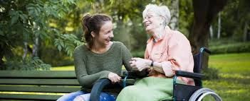 A woman is sitting on a bench next to an older woman in a wheelchair.