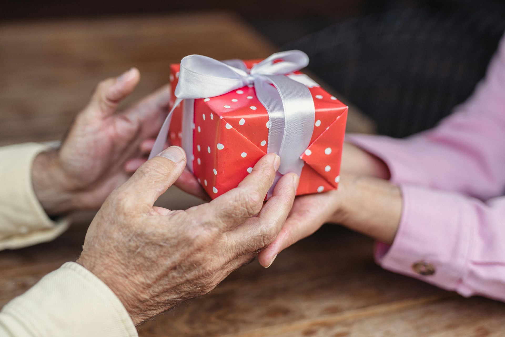 A woman is giving a gift to an older man.