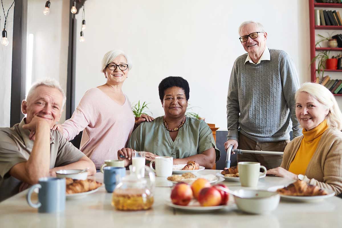 A group of elderly people are sitting at a table with food.