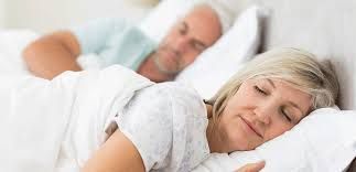 A man and a woman are sleeping in a bed.