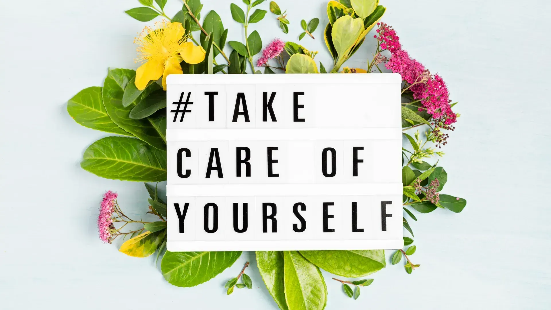 A sign that says `` take care of yourself '' is surrounded by flowers and leaves.