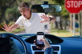 A man is standing in front of a stop sign while a person holds a cell phone.