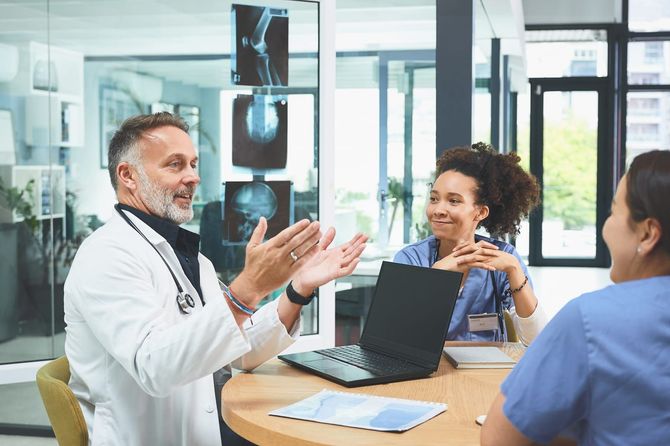 a group of doctors sharing their expertise around a table with a laptop