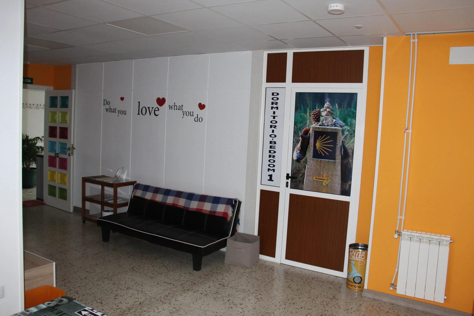 Hallway with white walls, black couch, orange accent wall, door with illustration.