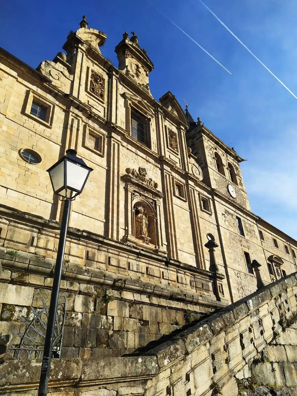 Stone building with ornate facade against a blue sky, street lamp in foreground.