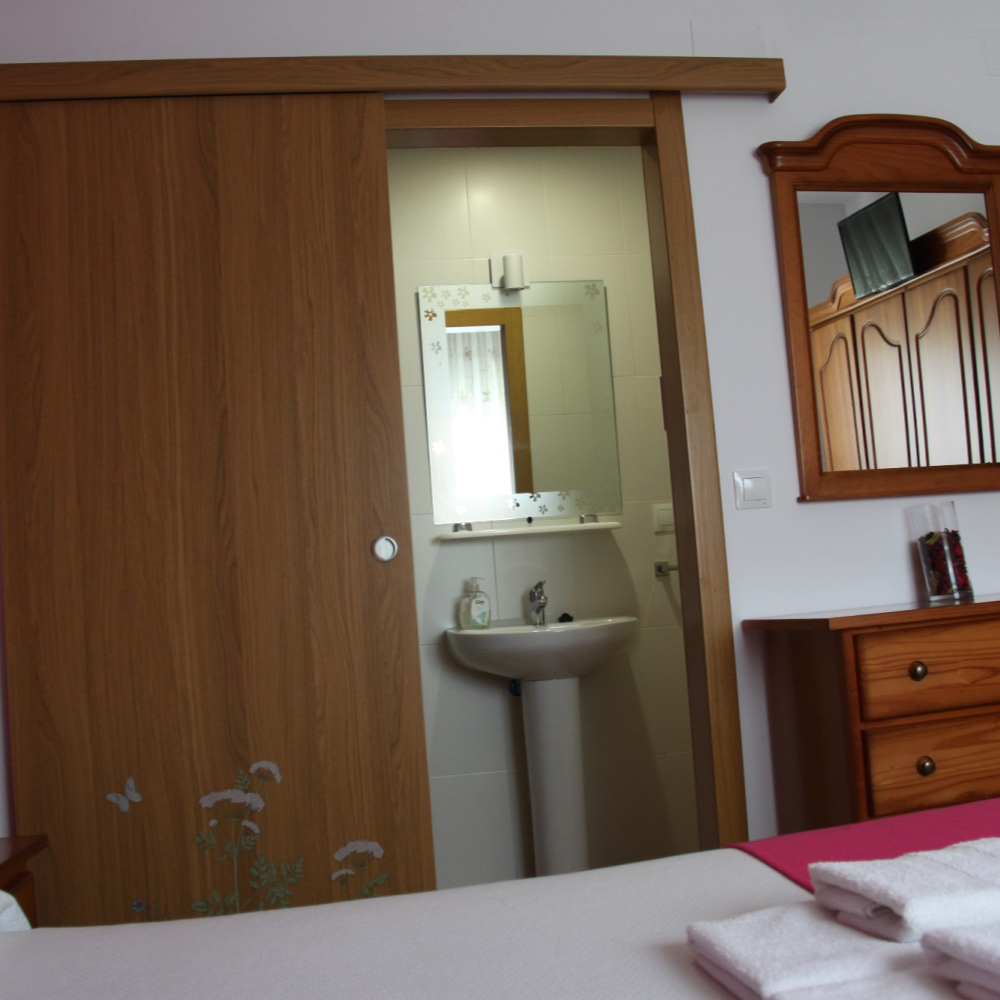 Bedroom with a partially open door to a bathroom, a mirror, and a dresser.
