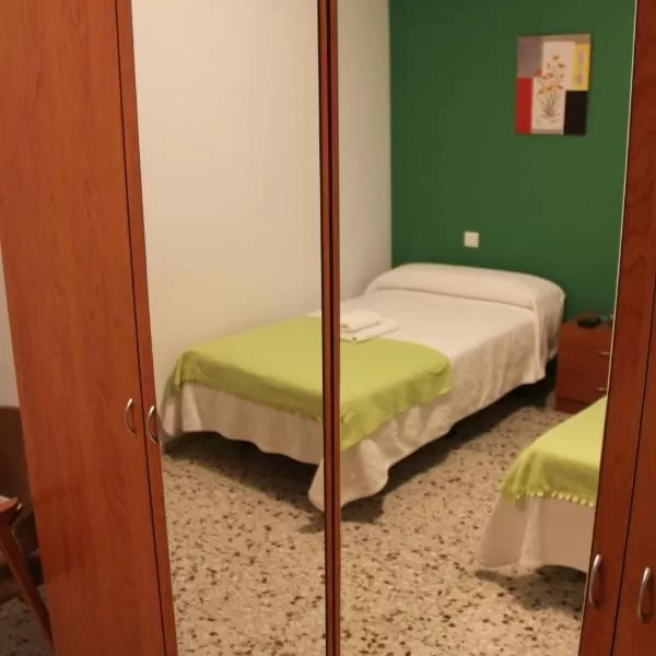 Reflection of a small bedroom with a single bed and green accents in a mirror.