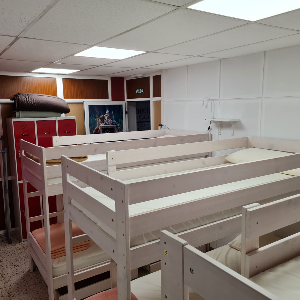 Bunk beds in a room. White, wooden frames, beige bedding. Red cabinets and paneling on walls.