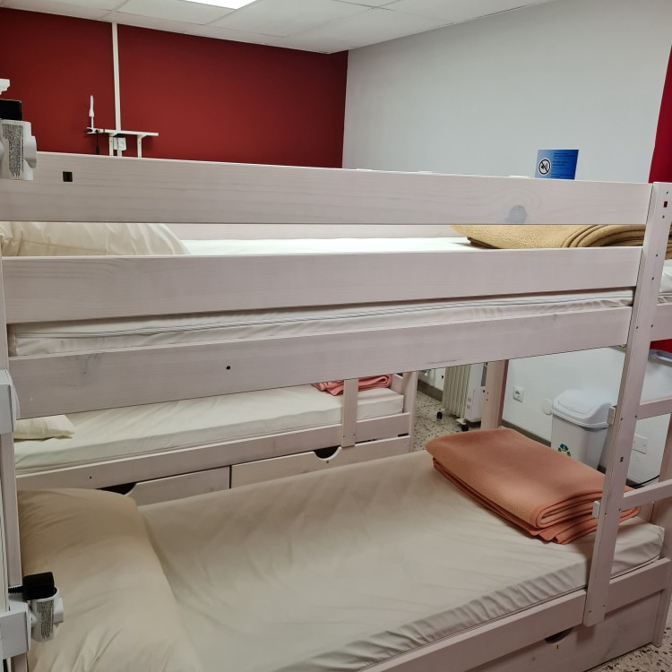 Bunk beds in a room with a red and white wall. Beige blankets are on the beds.