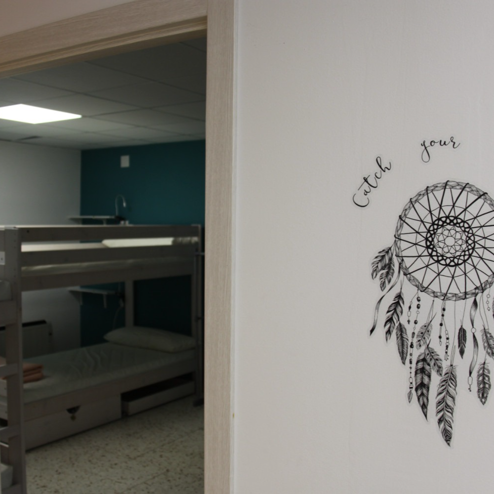 Bunk beds in a room, turquoise wall visible through the doorway, dreamcatcher decal on the wall.