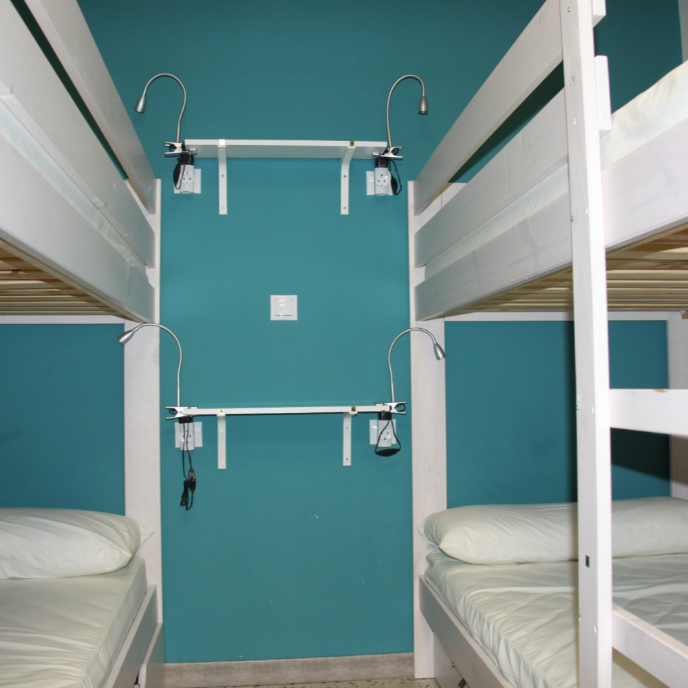 Bunk beds in a room, turquoise wall with reading lights and a power outlet.