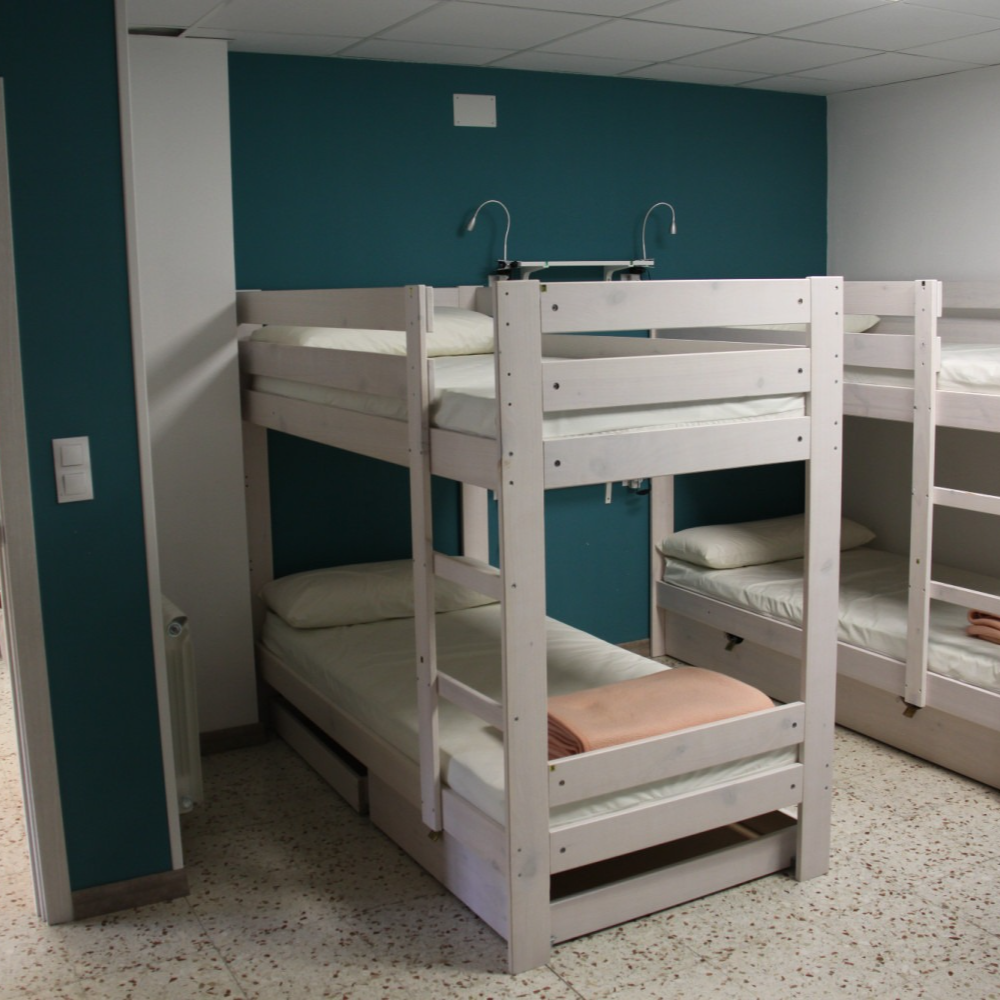 Bunk beds in a room with teal accent wall and white trim.  Pillows and bed linens are visible.