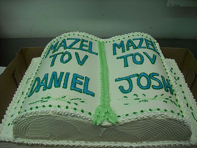 Cake shaped like an open book with green icing and the names Daniel and Josh, reading “Mazel Tov”
