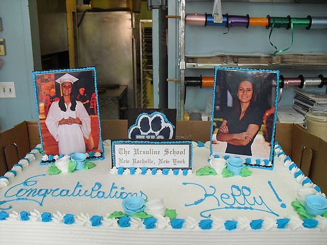 Decorated graduation cake with blue piping, two portrait photos, and a “Congratulations” message