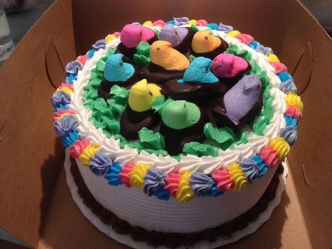 Decorated cake with colorful frosting and candy on top, inside a cardboard box