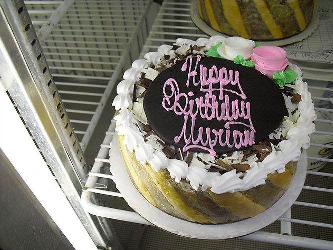 Birthday cake with pink icing reading “Happy Birthday Vivian” on a refrigerator shelf
