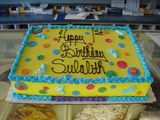 Assorted decorated holiday cakes and cookie wreaths with red, green, and white frosting on a tray