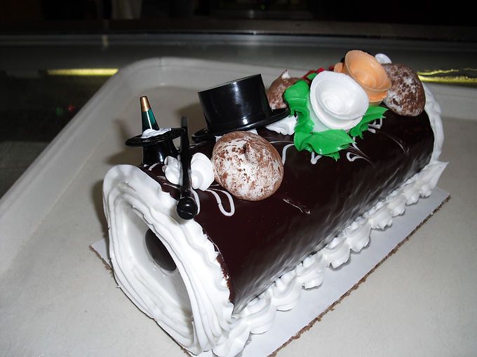 Chocolate Yule log cake with white frosting and assorted candies on a white platter