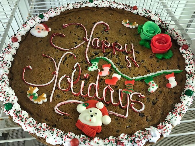 Decorated chocolate cake with “Happy Holidays” icing, red and green roses, and Santa figurines