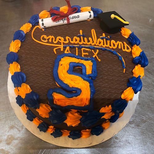 Chocolate cake with blue and orange frosting, “Congratulations Alex,” and a large orange-blue S on top