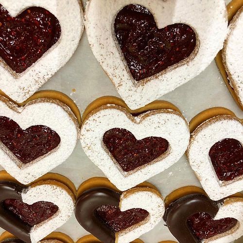 Heart-shaped cookies with white icing and dark red centers arranged in a grid