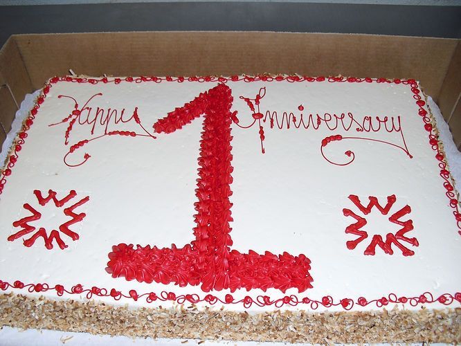 Red-and-white cake with a large number 1 and “Happy Anniversary” written on top.