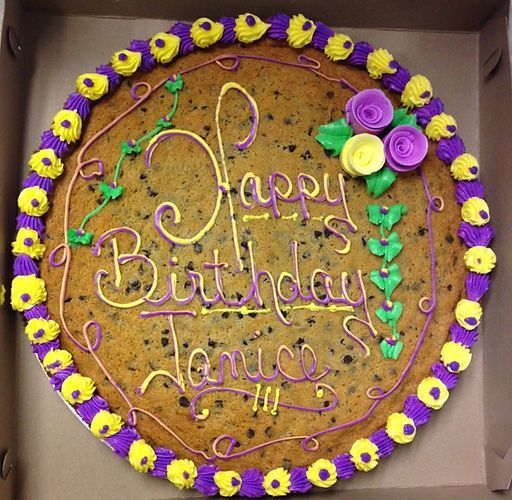 Birthday cake with purple and yellow flowers and “Happy Birthday Jennie” written on top
