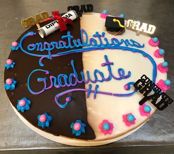 Decorated graduation cake with blue icing text and black, white, and pink accents