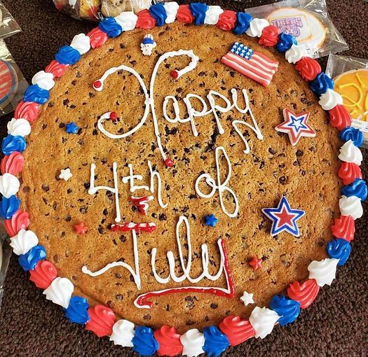Round cookie cake with red, white, and blue icing reading “Happy 4th of July” and patriotic stars.