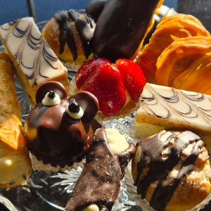 Assorted chocolate and fruit pastries on a plate, including strawberries, orange slices, and cream-filled treats