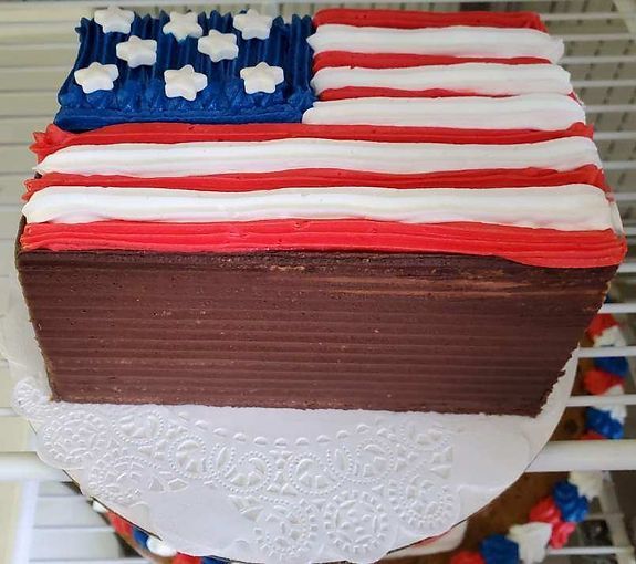Patriotic red, white, and blue cake topped with an American flag design and white icing trim