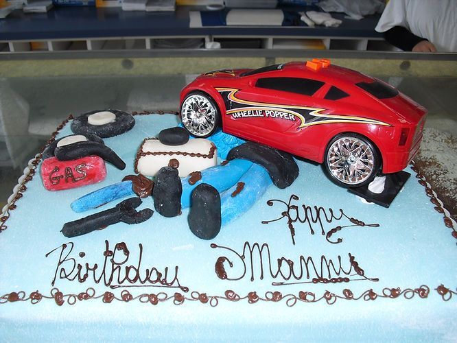 Red toy race car and birthday decorations on a cake with “Birthday Mama” written in icing
