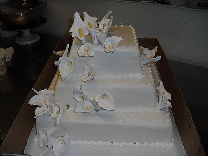 White tiered wedding cake with white flowers on a table