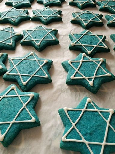 Teal star-shaped cookies topped with white icing stars on a tray