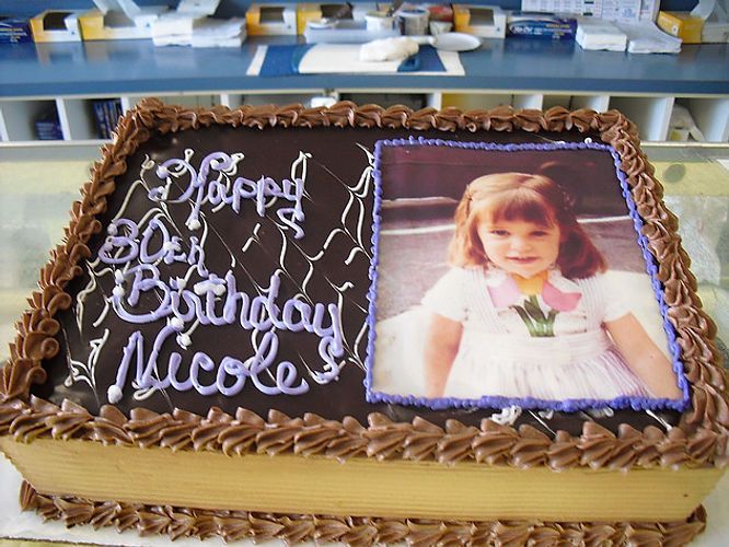 Chocolate birthday cake with white icing message and a child’s photo on top
