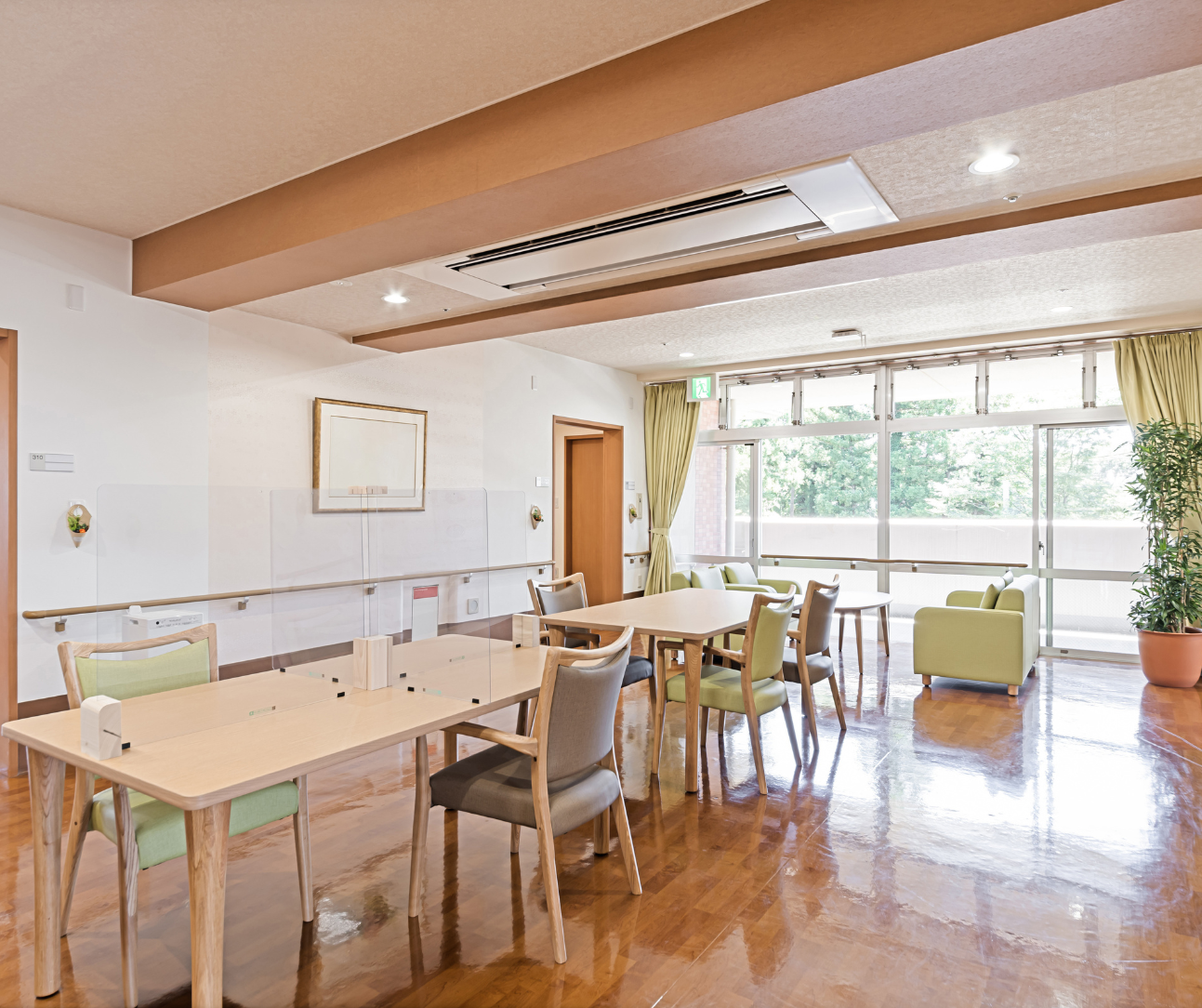 A brightly lit room with tables and chairs, likely a communal space in a care facility.