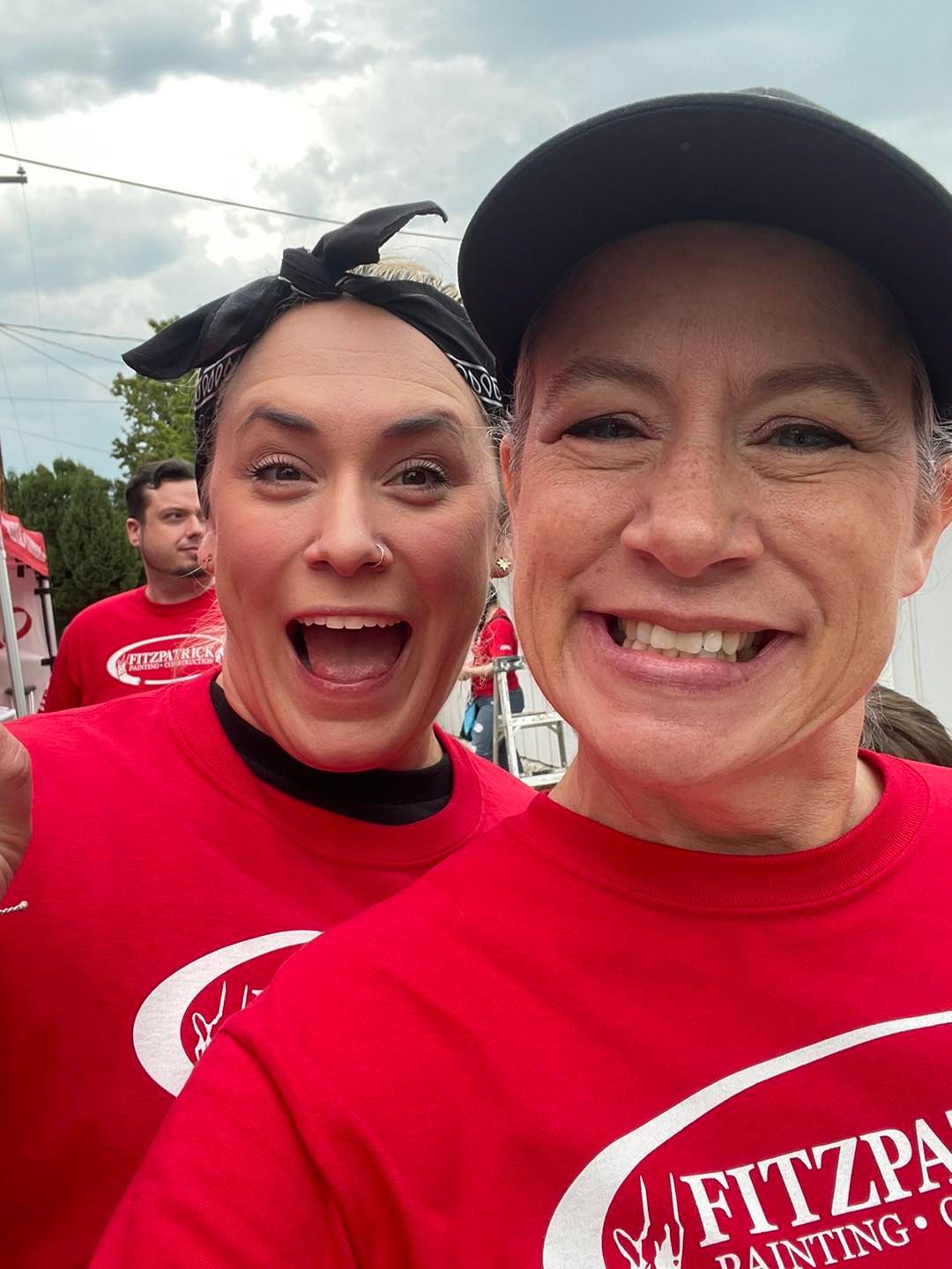 Two people in red shirts smile for a selfie outdoors