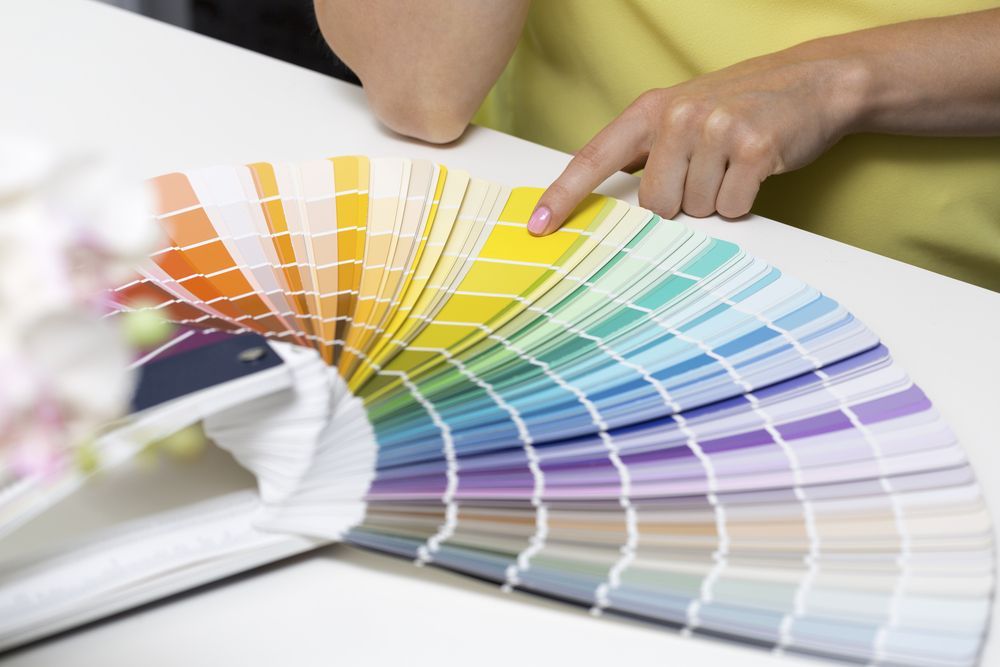 A person is pointing at a color palette on a table.